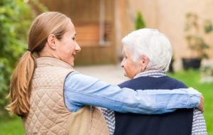 Young carer walking with the elderly woman in the park